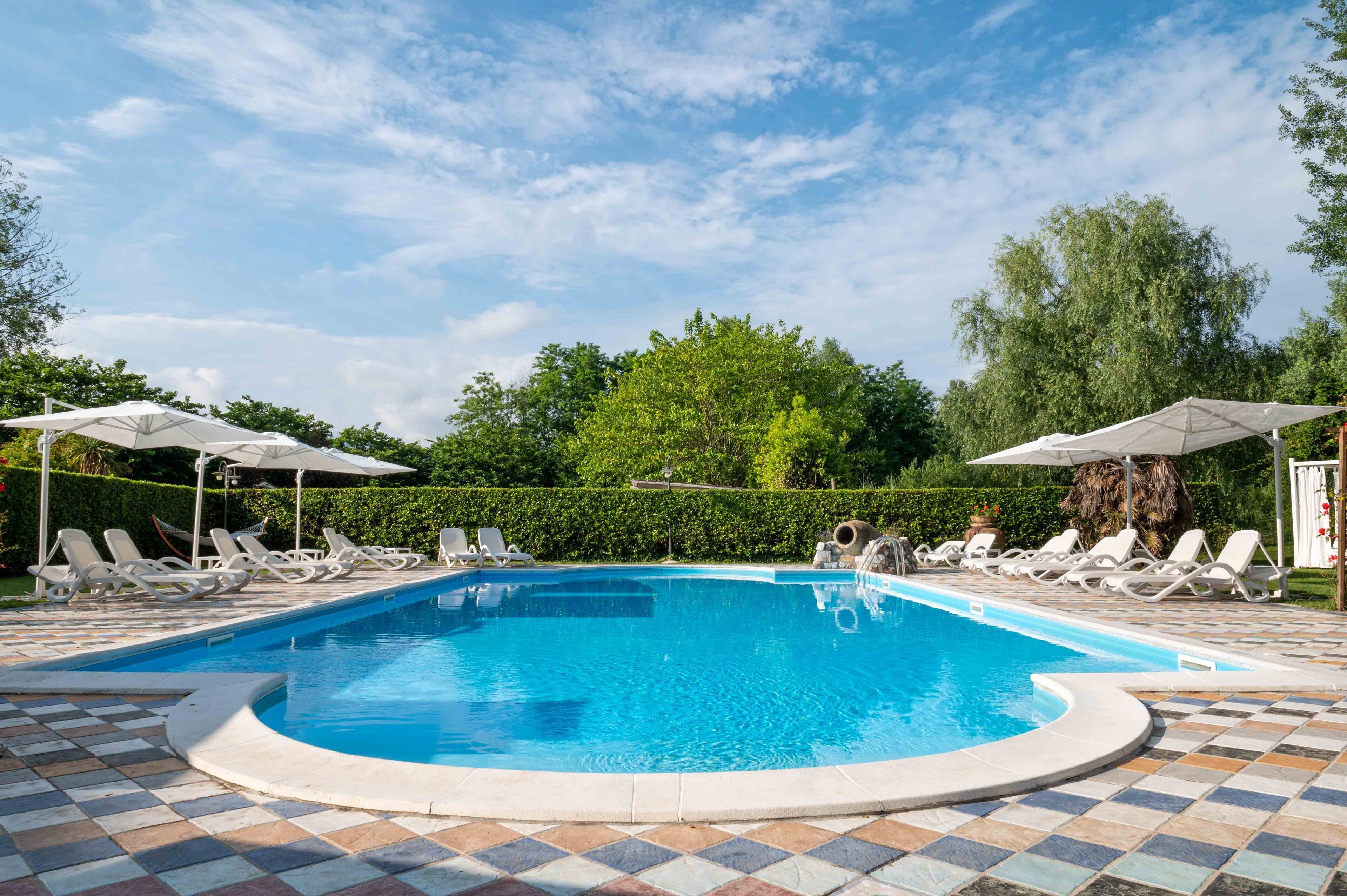 Una piscina con lettini e ombrelloni, immersa nel verde.