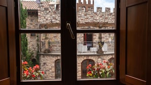 A view through a wooden door with a stone building in the background, featuring balconies and arched windows. - Villa Corte Degli Dei (Lucca)