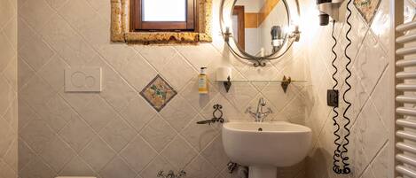 A bathroom with a toilet, bidet, sink, and a hairdryer mounted on the wall.