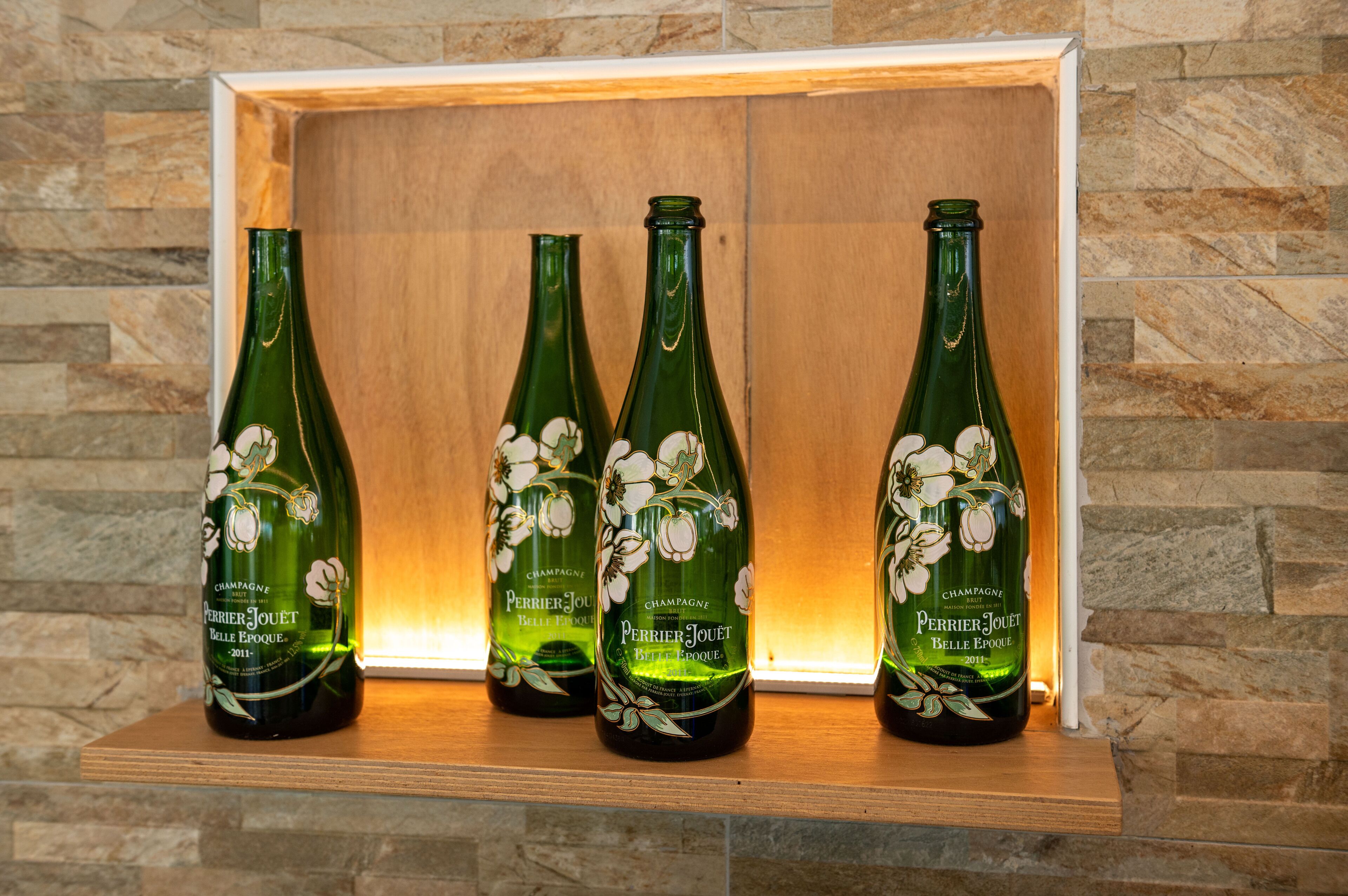 Quattro bottiglie di champagne Perrier Jouët Belle Époque in un espositore di legno.