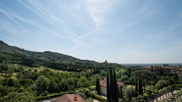 Una villa circondata da verde lussureggiante e colline, con un cielo sereno.