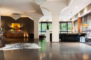 A spacious lobby with a modern chandelier, a large zebra print rug, and a black leather sofa. - Hotel Michelangelo & Spa (Montecatini Terme)