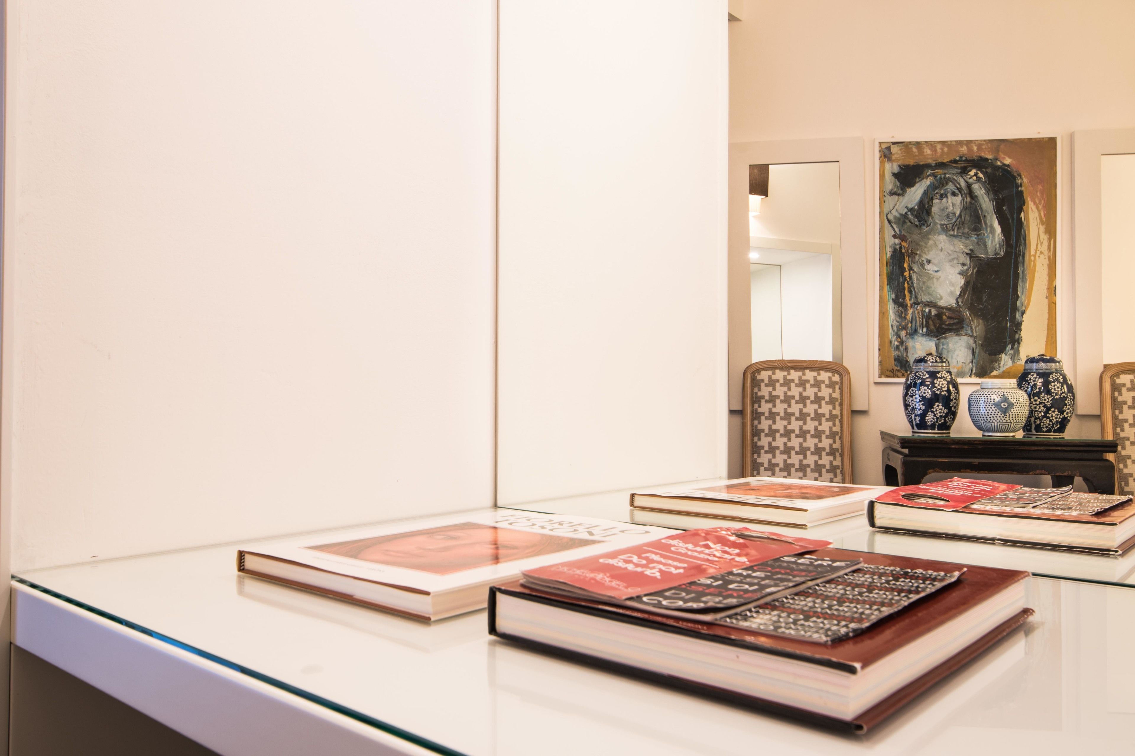 Een kamer met een glazen tafel waarop boeken en decoratieve objecten staan.