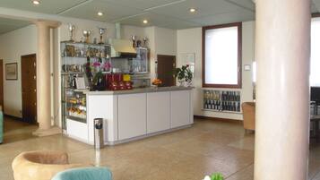Un vaste espace de vie doté d’un îlot central, d’une cuisine avec un meuble à vin et d’une grande fenêtre.