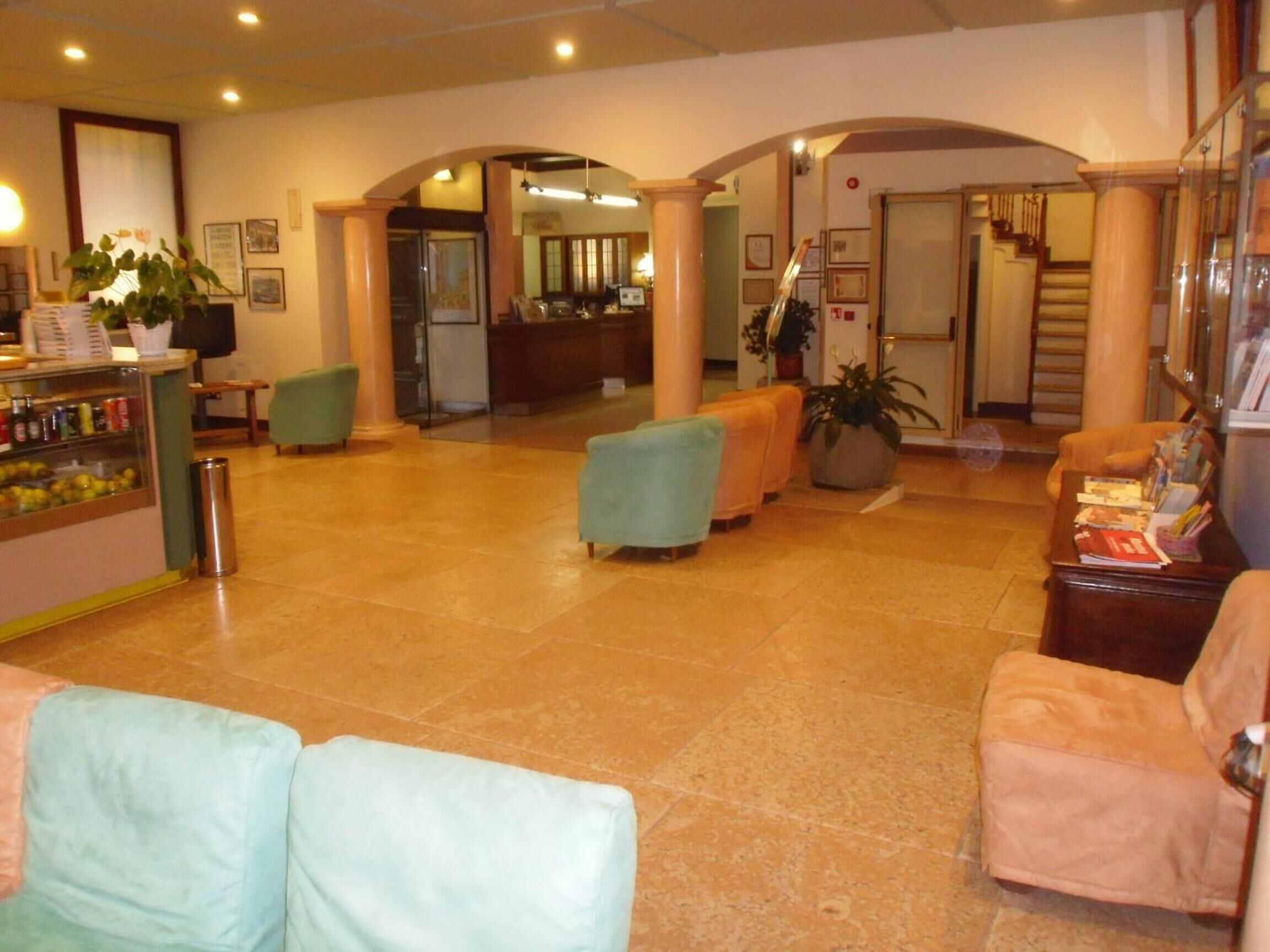 A spacious lobby with a reception desk, seating area, and a staircase leading to upper floors.
