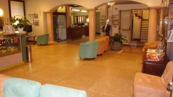 A spacious lobby with a reception desk, seating area, and a staircase leading to upper floors.