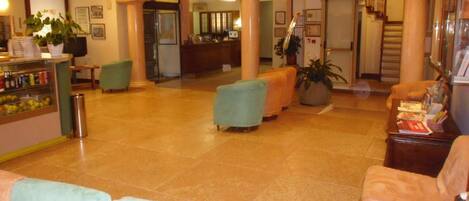 A spacious lobby with a reception desk, seating area, and a staircase leading to upper floors.