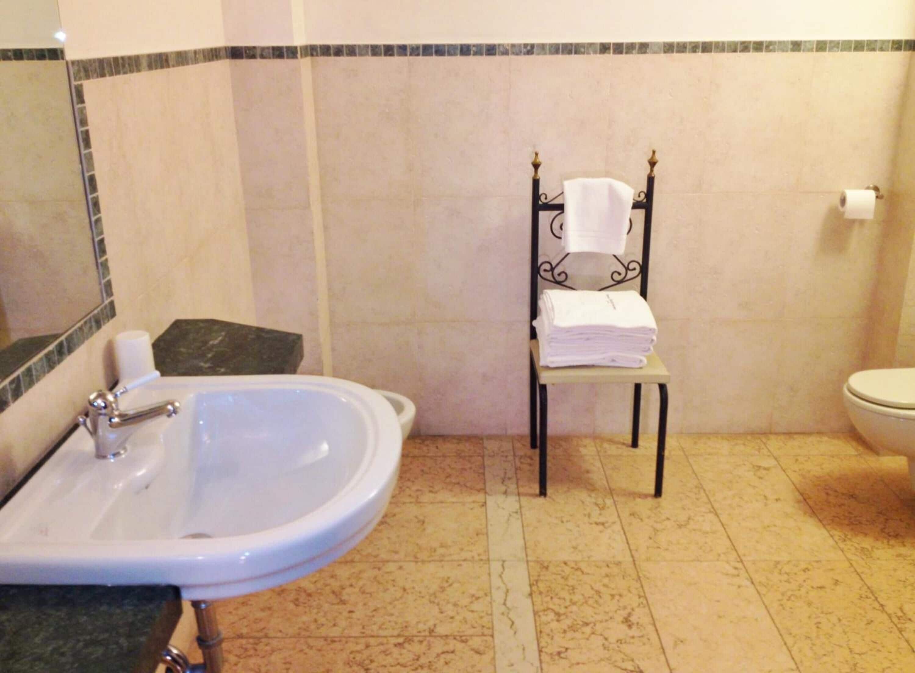 Ein Badezimmer mit Waschbecken, Toilette und einem Stuhl mit Handtüchern.