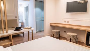 Ein modernes Hotelzimmer mit einem Bett, einem Schreibtisch, einem an der Wand befestigten Fernseher und einem kleinen Hocker.
