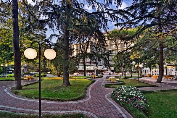 A landscaped courtyard with a brick pathway, outdoor seating, and trees.
