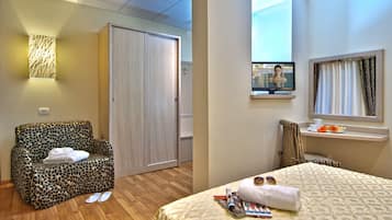 Een hotelkamer met een slaapbank, een bed, een televisie en een raam met gordijnen.