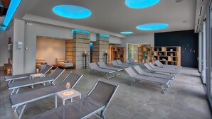 Un área de spa moderna con tumbonas, un mostrador de recepción y un amplio ventanal.