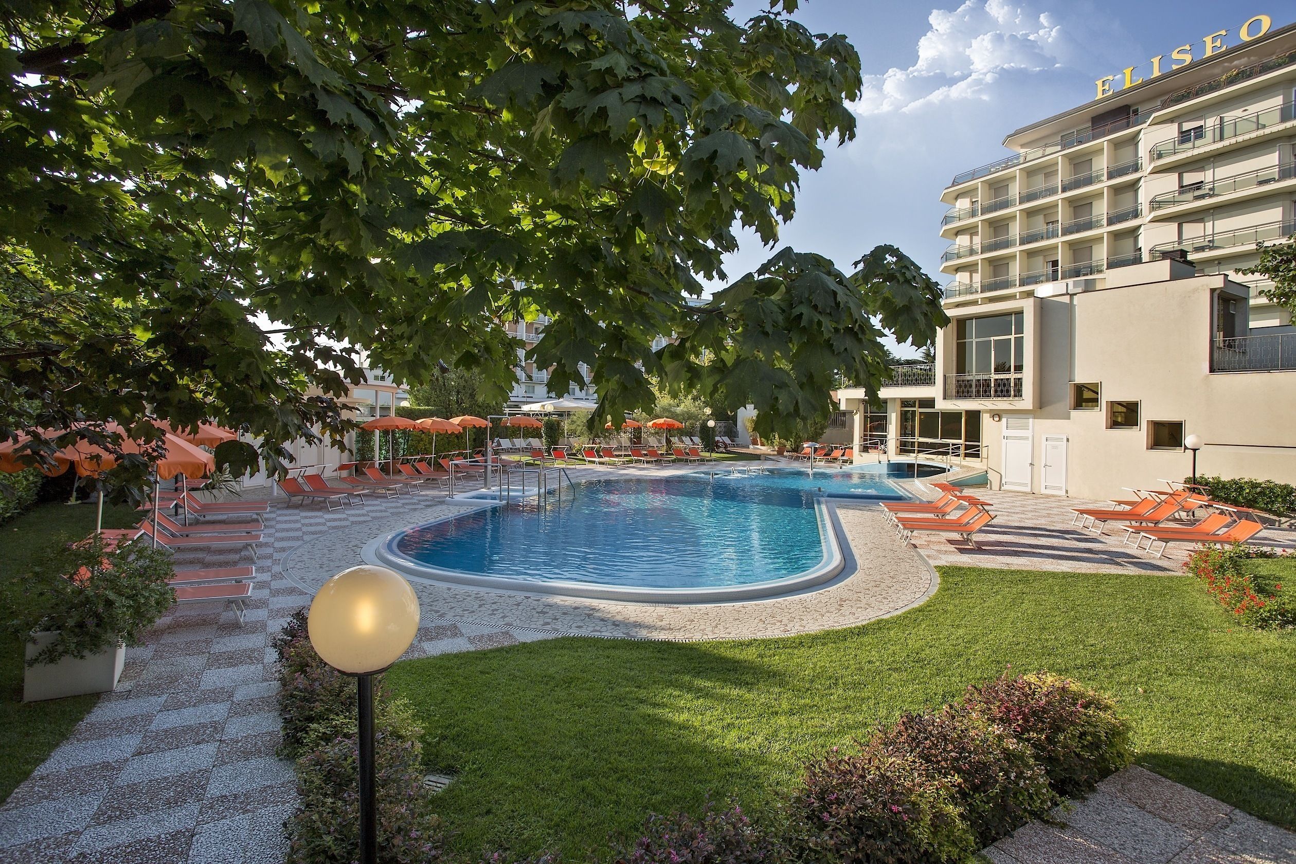 Un hotel con piscina, mobiliario exterior y un jardín bien cuidado.
