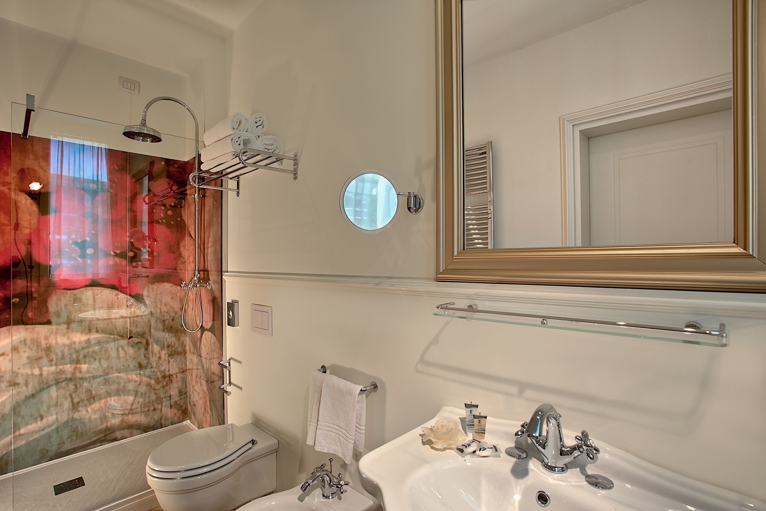 Ein Badezimmer mit Duschkabine, Toilette, Waschbecken mit Spiegel und Handtuchhalter.