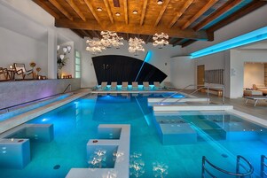 Una piscina techada, una piscina al aire libre, sombrillas