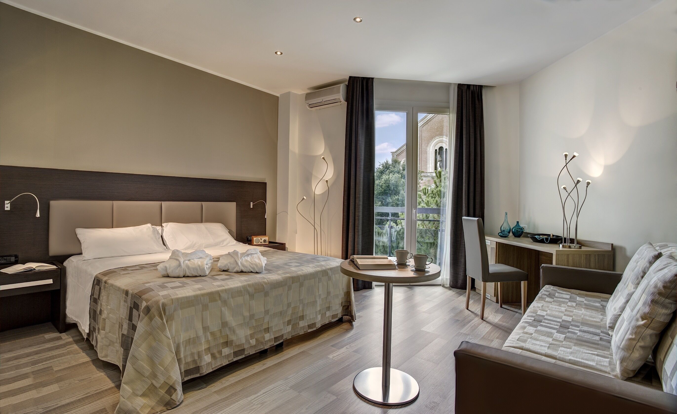 Una habitación de hotel moderna con una cama grande, un escritorio, una silla y un balcón con vistas.