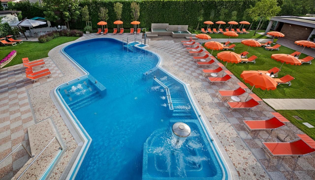 A swimming pool with a checkered deck, surrounded by lounge chairs and umbrellas.
