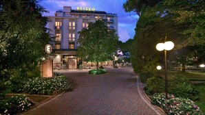 Hotel Eliseo, con una entrada bien iluminada, sendero pavimentado y jardines ajardinados.