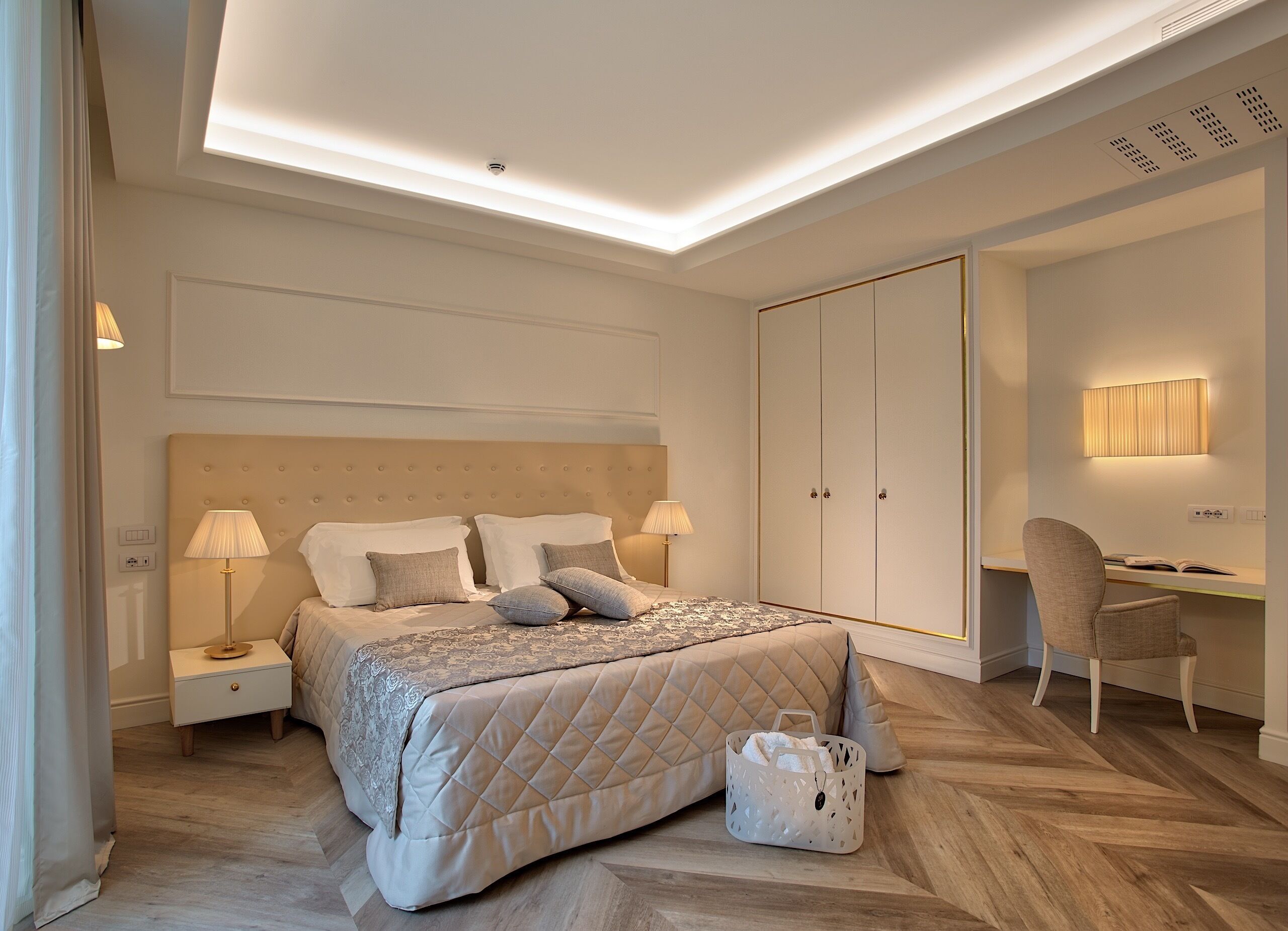 Une chambre moderne avec un grand lit, des lampes de chevet, un bureau avec une chaise et une armoire.