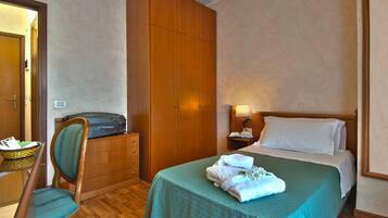 Ein Hotelzimmer mit einem Bett, einem Holzschrank, einem Schreibtisch mit einer Lampe und einem Stuhl.