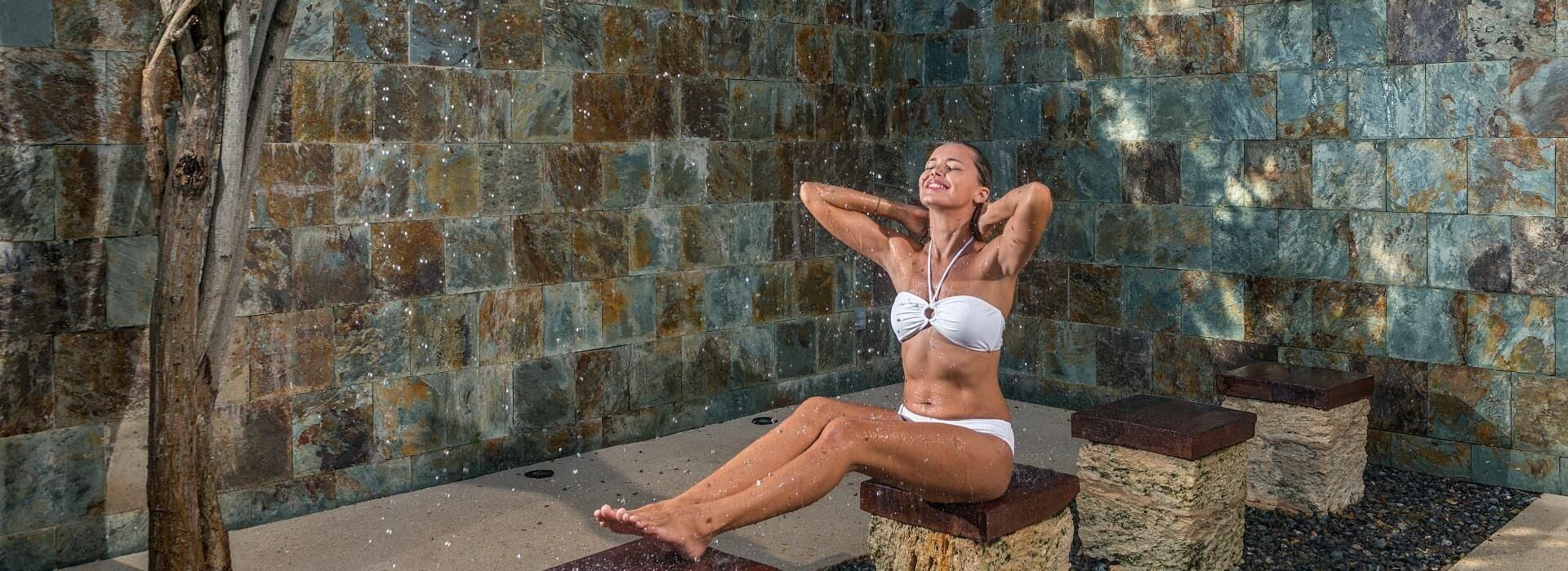 Una persona sentada en un banco de piedra en un espacio con paredes de piedra.