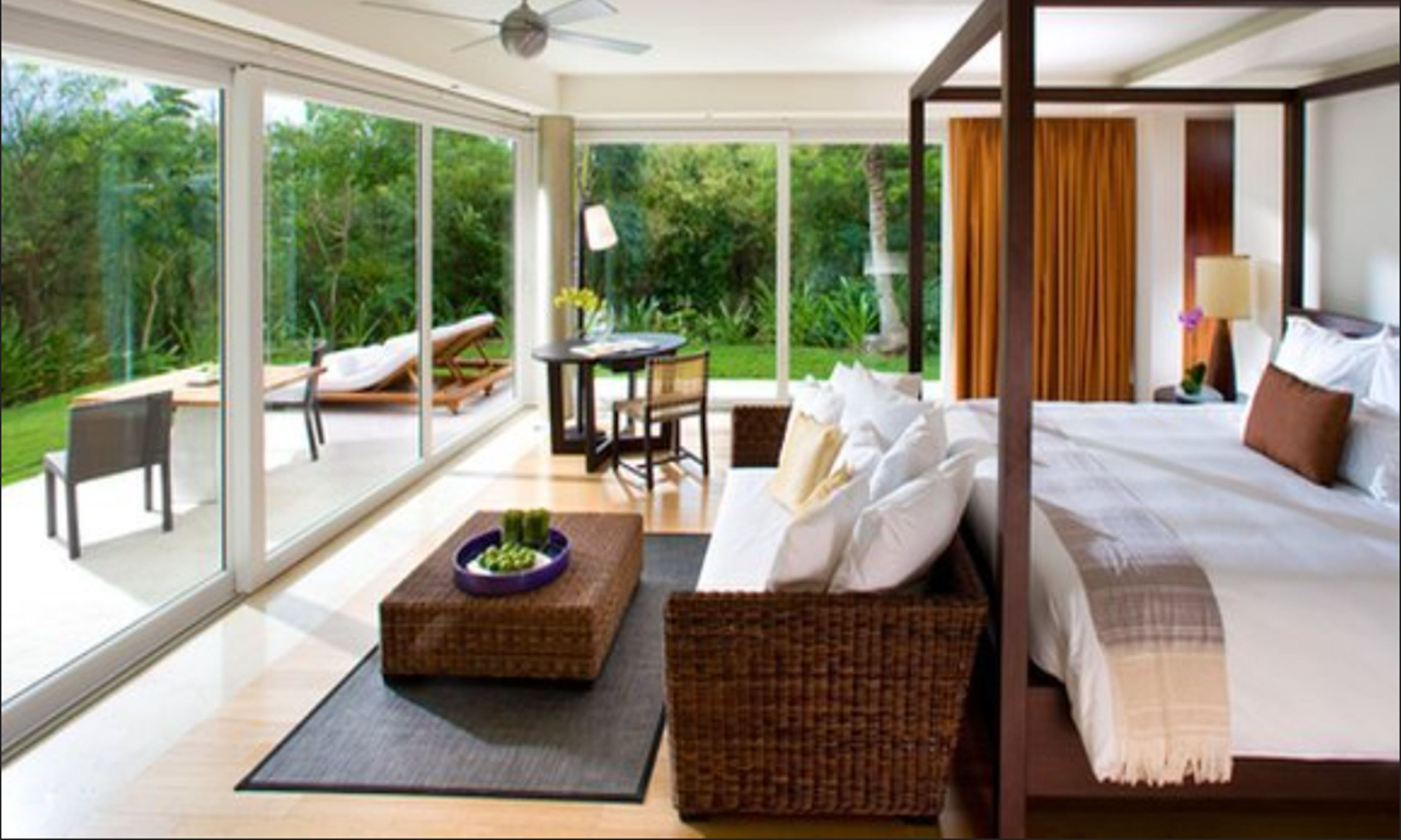 Une chambre à coucher moderne avec un lit à baldaquin, un canapé en osier et un coin repas comprenant une table et des chaises.