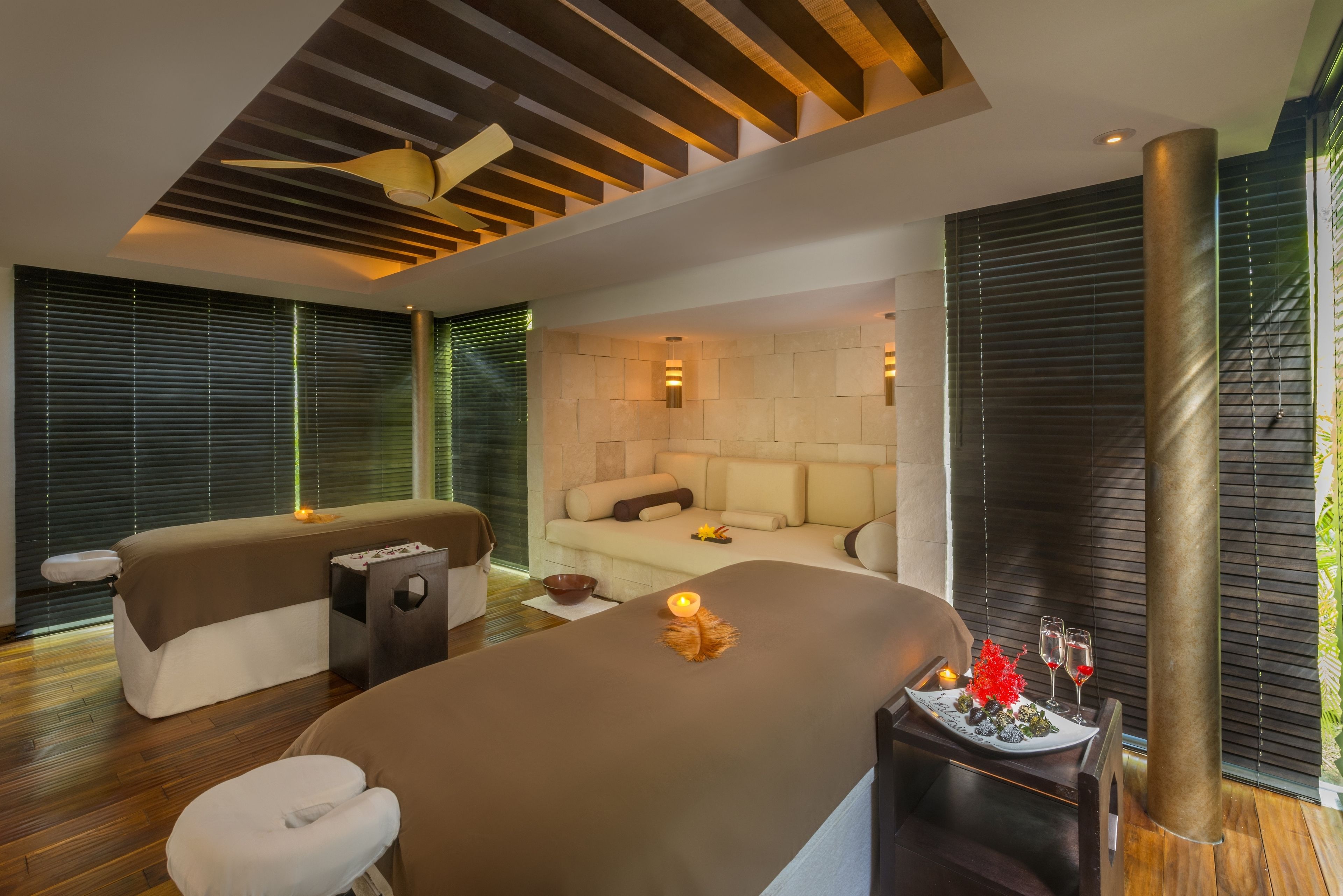Un spa moderno con una camilla de masaje, un sofá y una zona de comedor con velas y copas.