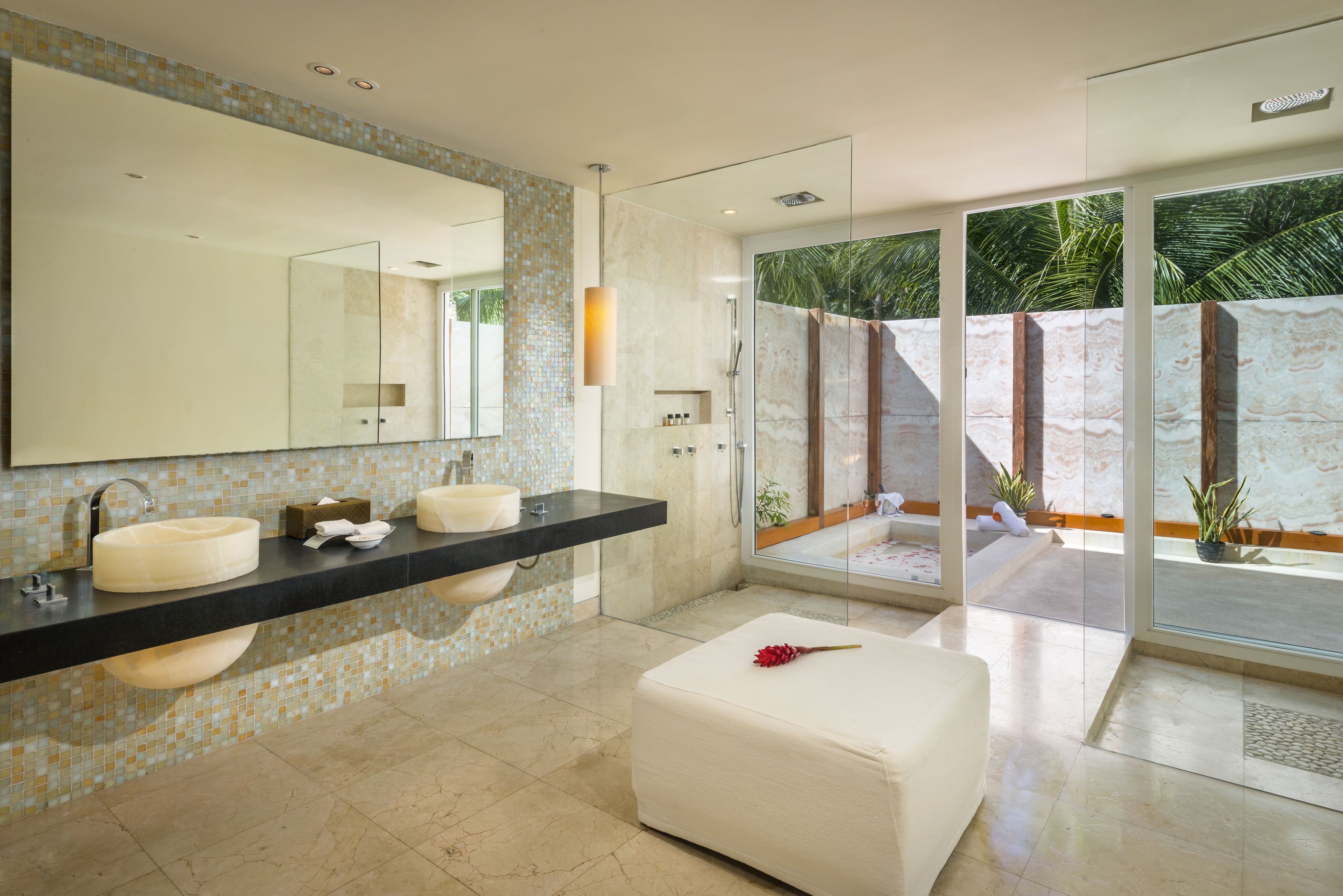 A modern bathroom with a large mirror, two sinks, and a glass shower enclosure.
