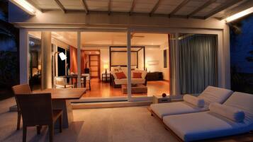 Un interior moderno con comedor, sala de estar con sofá y televisor, y un dormitorio con cama y cortinas.