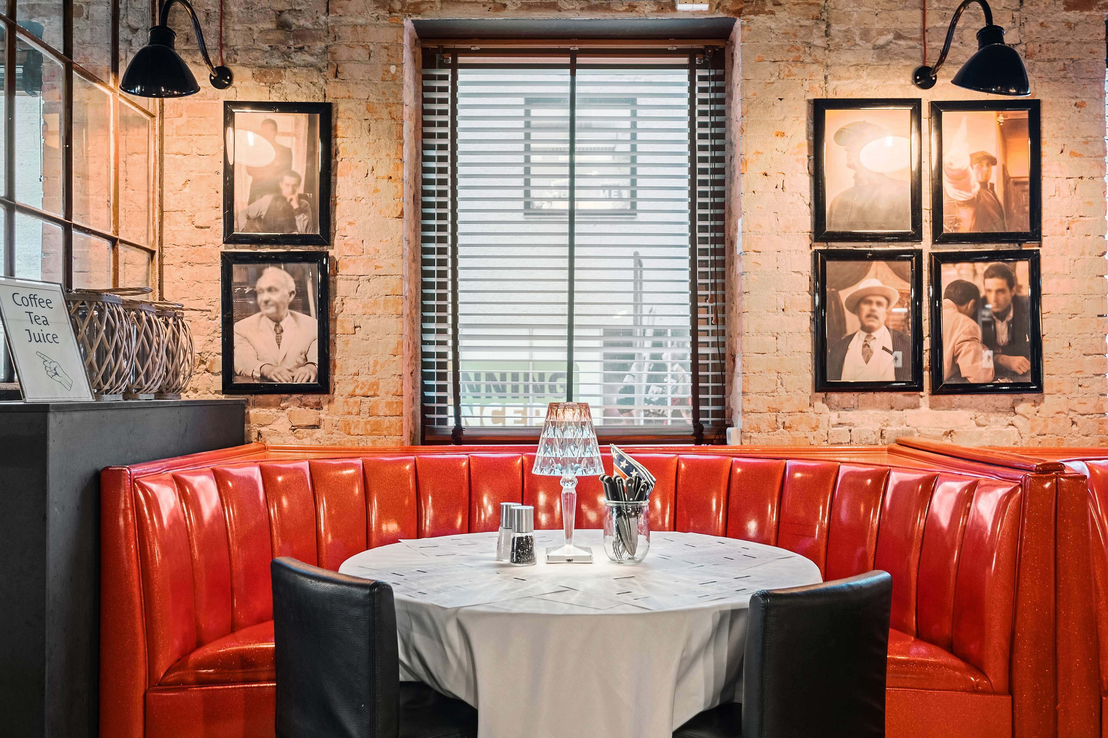 Un restaurante con asientos de cuero rojo, una mesa redonda con mantel blanco y cuadros en la pared.
