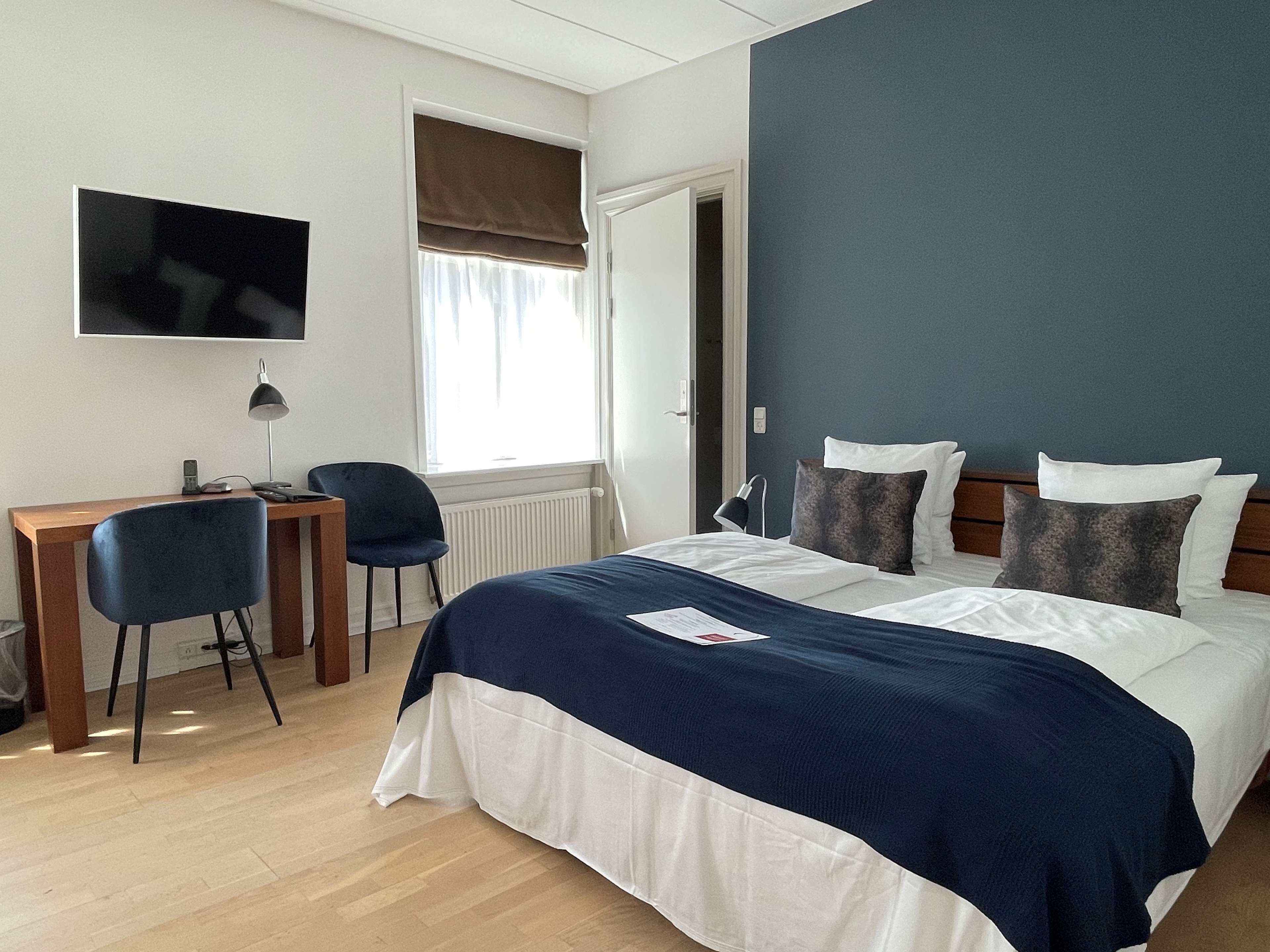 Habitación de hotel con cama, escritorio, silla, televisor y ventana con vistas.