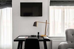 A modern room with a flat-screen TV mounted on the wall, a desk with a lamp, a chair, and a radiator. - Best Western Hotel Herman Bang (Frederikshavn)