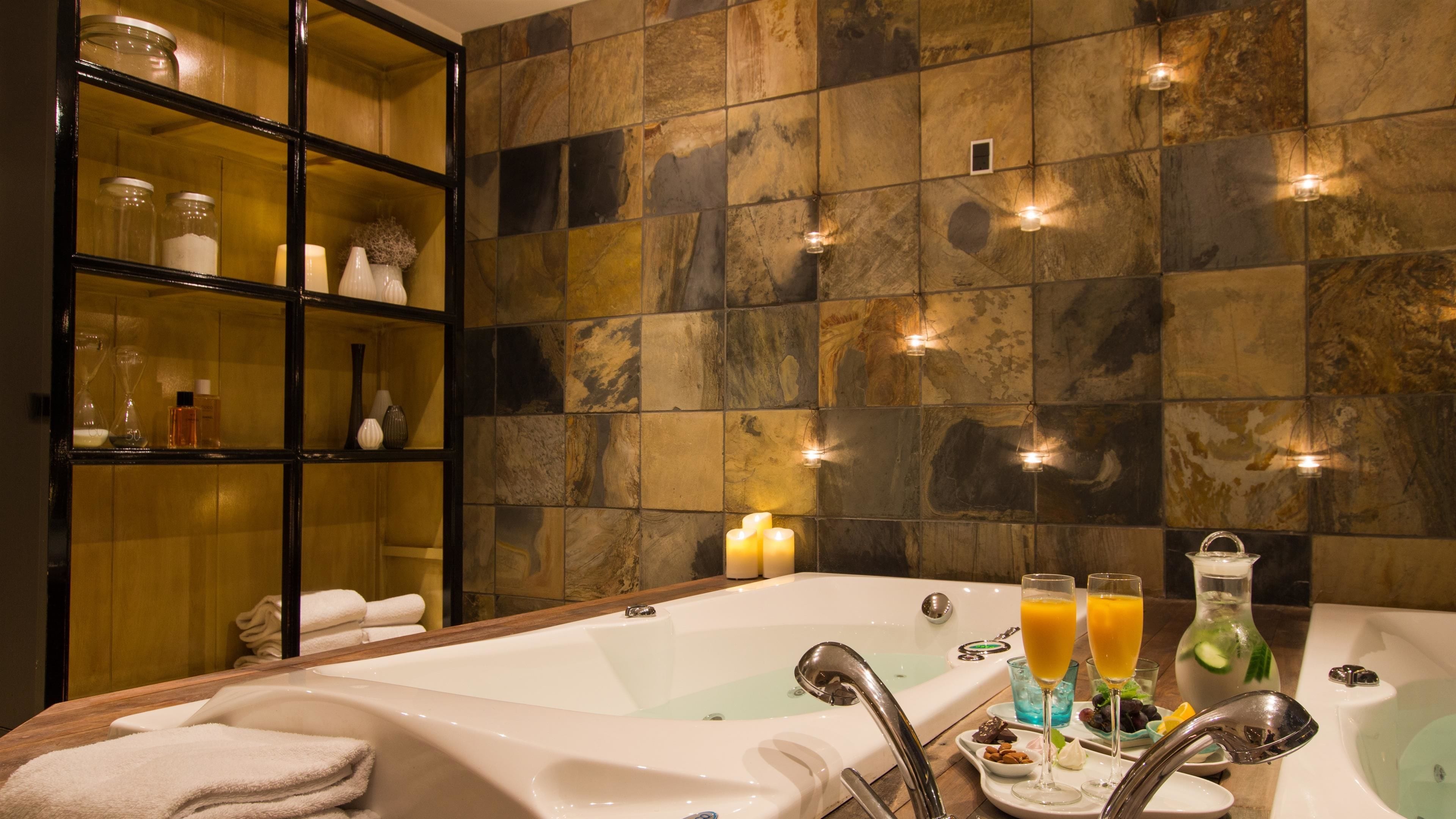 A bathroom with a bathtub, a glass shower enclosure, and a shelf with toiletries.