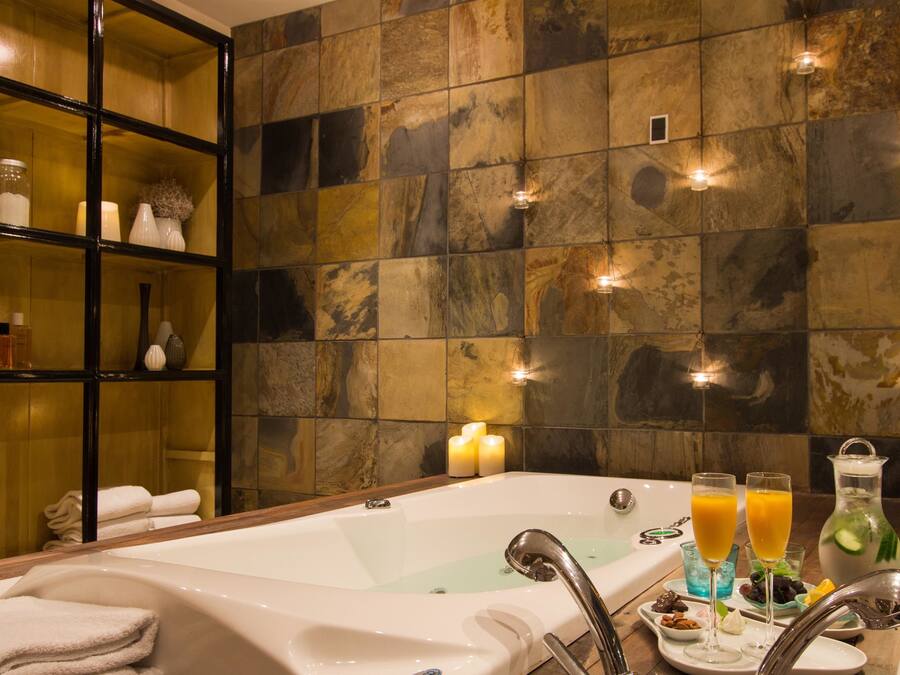 A bathroom with a bathtub, a glass shower enclosure, and a shelf with toiletries.