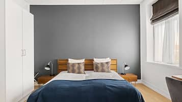 A bedroom with a bed, bedside tables, a wardrobe, and a window with curtains.
