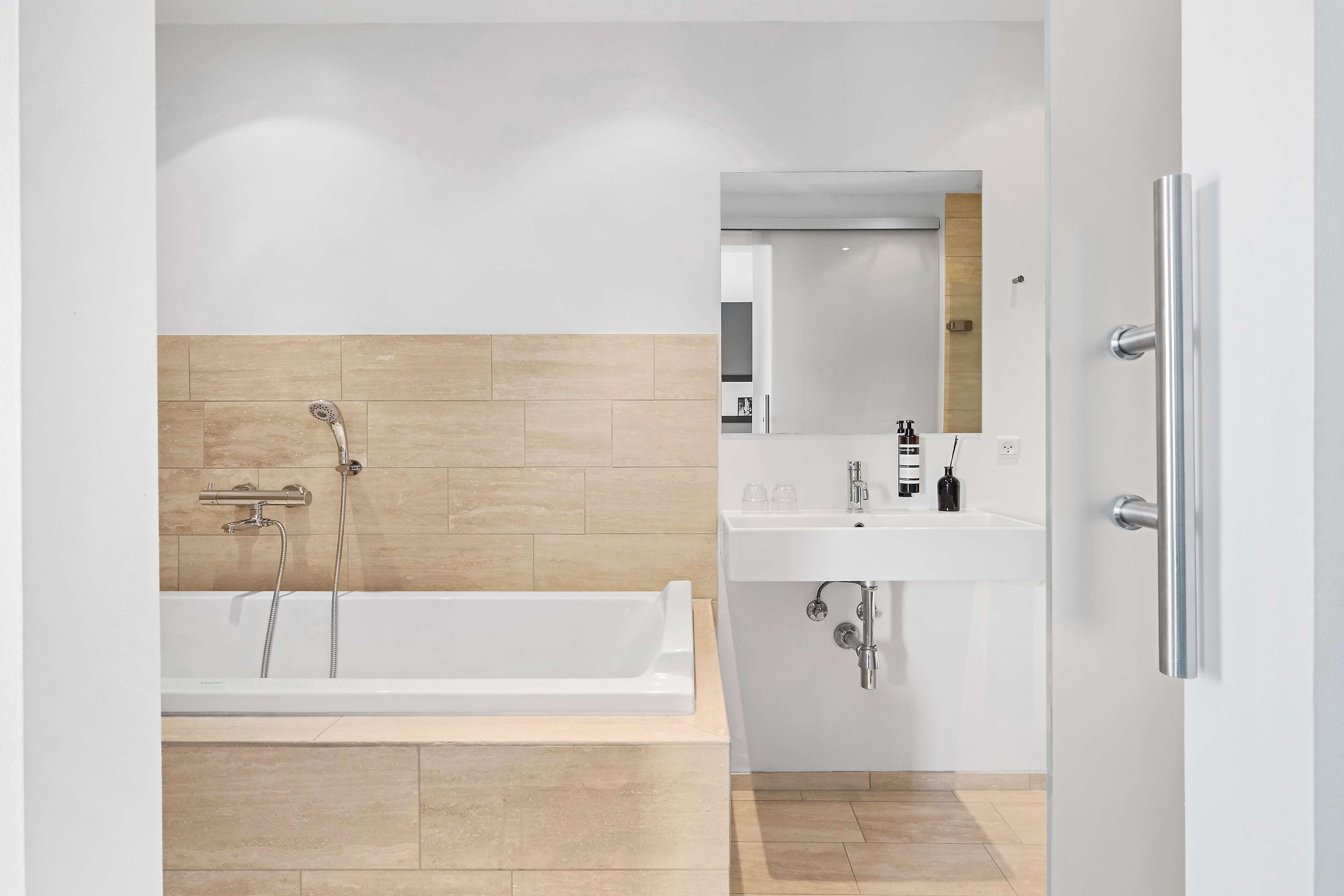 A modern bathroom with a bathtub, a sink, and a mirror.
