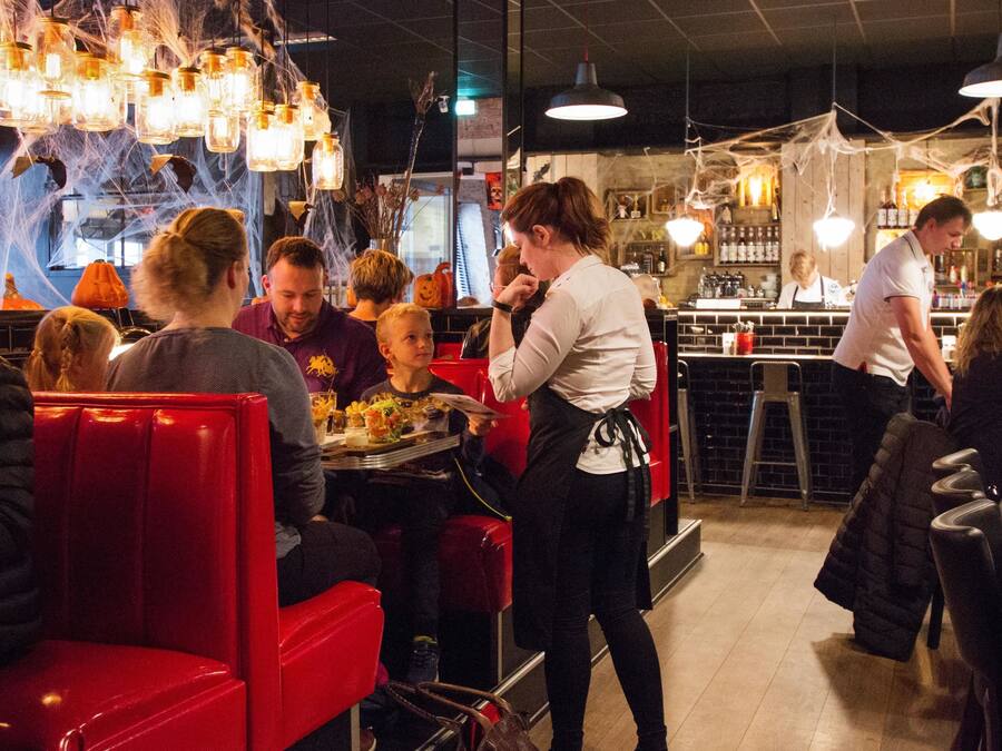 Un interior de restaurante con cabinas rojas, lámparas colgantes y una zona de bar.