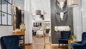 Un interior moderno con sillones azul oscuro, una zona de comedor con mantel blanco y decoración en la pared que incluye un cráneo de vaca.