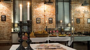 En restaurang med tegelväggar, levande ljus och ett varierat utbud av mat som presenteras på borden.