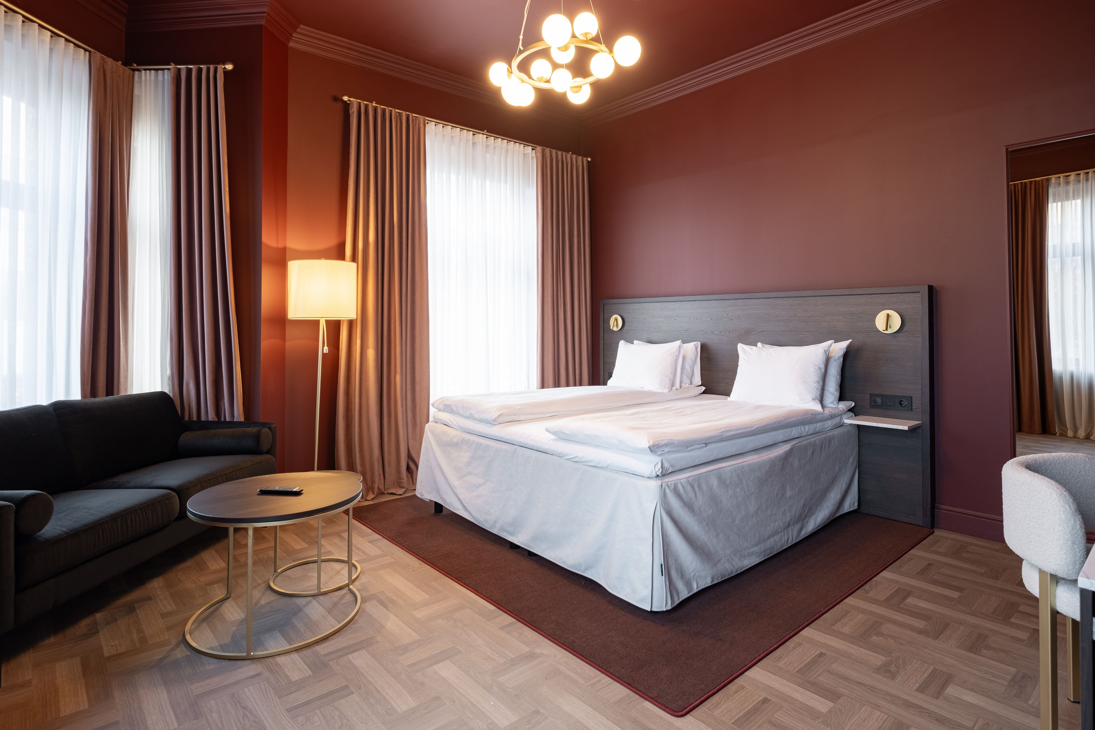 Une chambre d’hôtel avec un lit, un canapé, une petite table et une lampe.