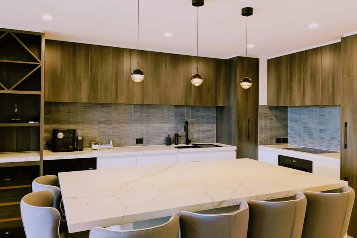 A modern kitchen with a large island, pendant lights, and built-in cabinetry.