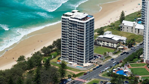 A high-rise hotel with multiple balconies overlooking a beach and ocean.