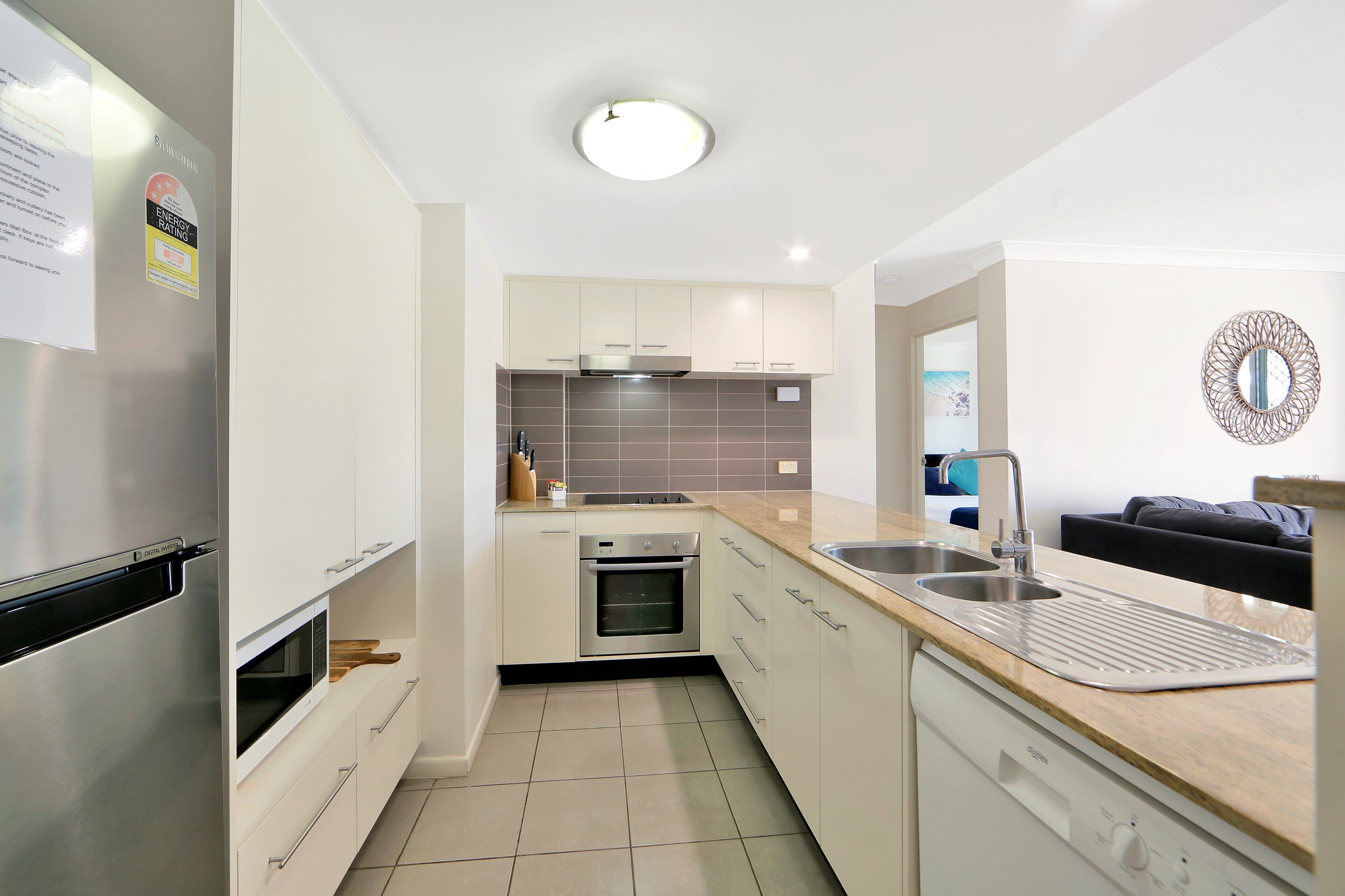 Een moderne keuken met witte kasten, roestvrijstalen apparatuur en een betegelde achterwand.