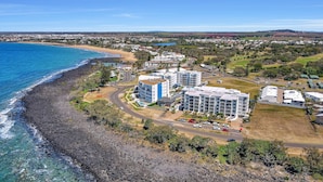 Vue aérienne d’une zone côtière comprenant une plage, des immeubles résidentiels et une route.