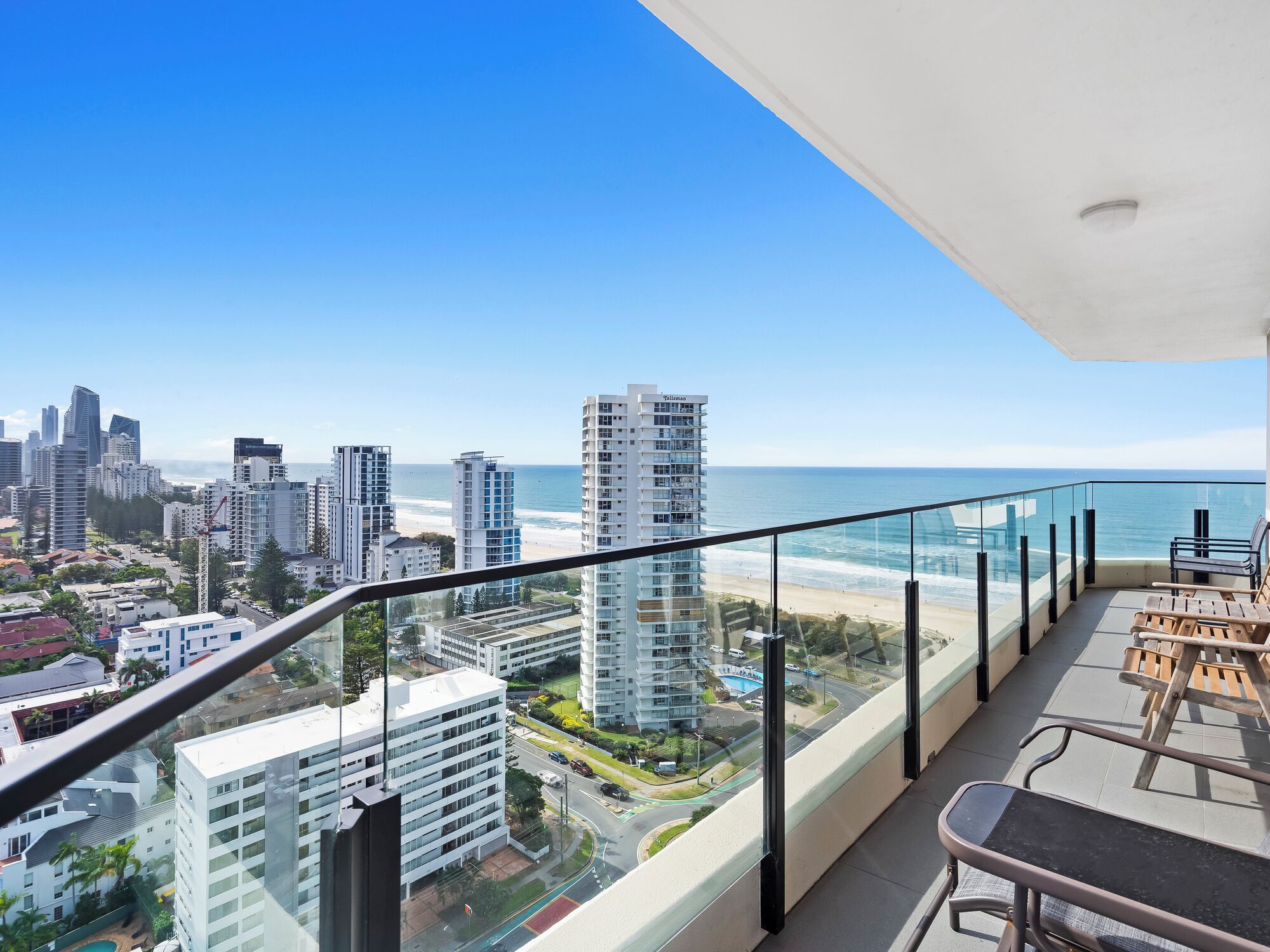 Varanda com vista para a praia e o horizonte urbano, com edifícios modernos e céu claro.