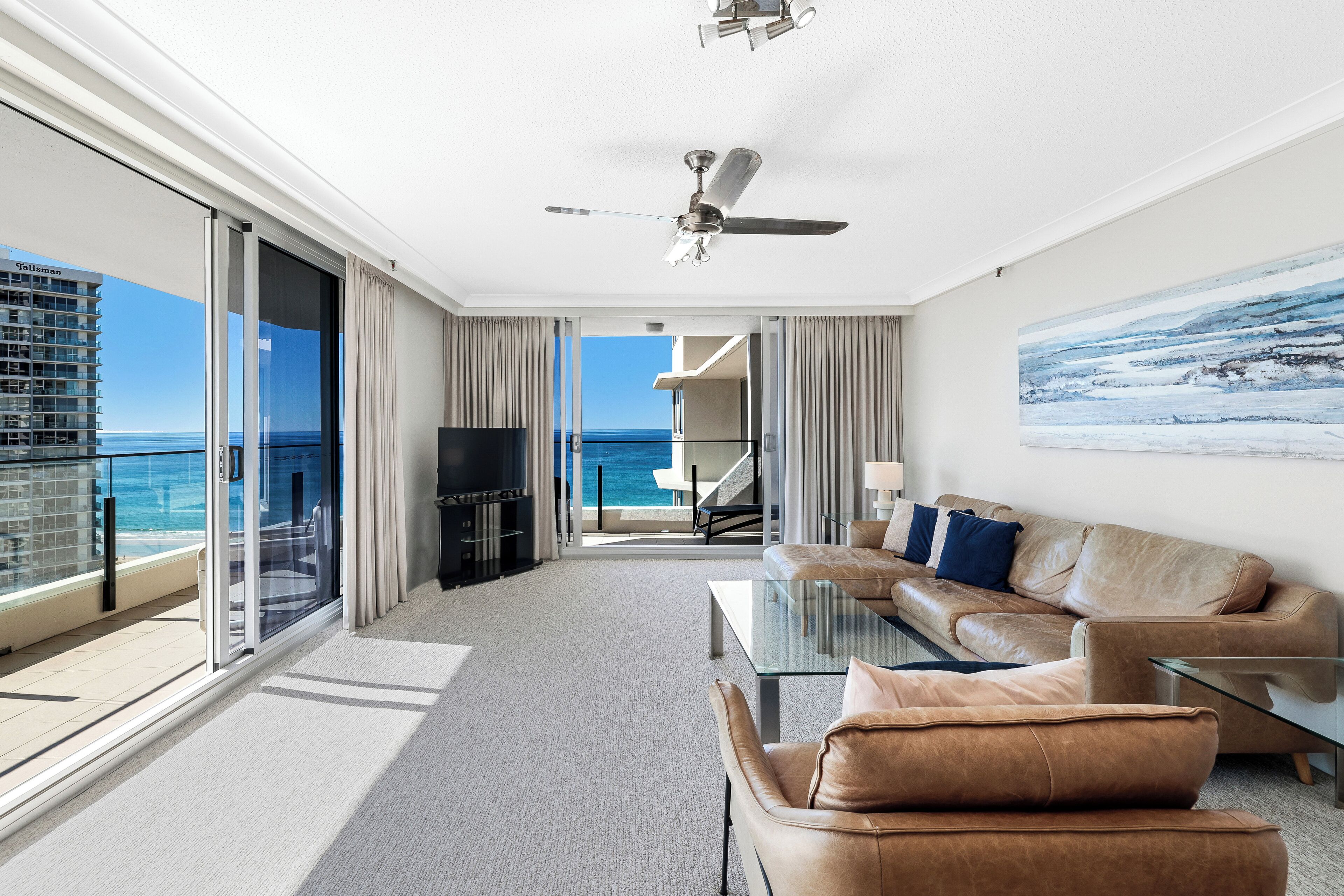A modern hotel room with a balcony, a sofa, a coffee table, and a TV.