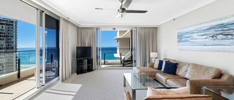 A modern hotel room with a balcony, a sofa, a coffee table, and a TV.