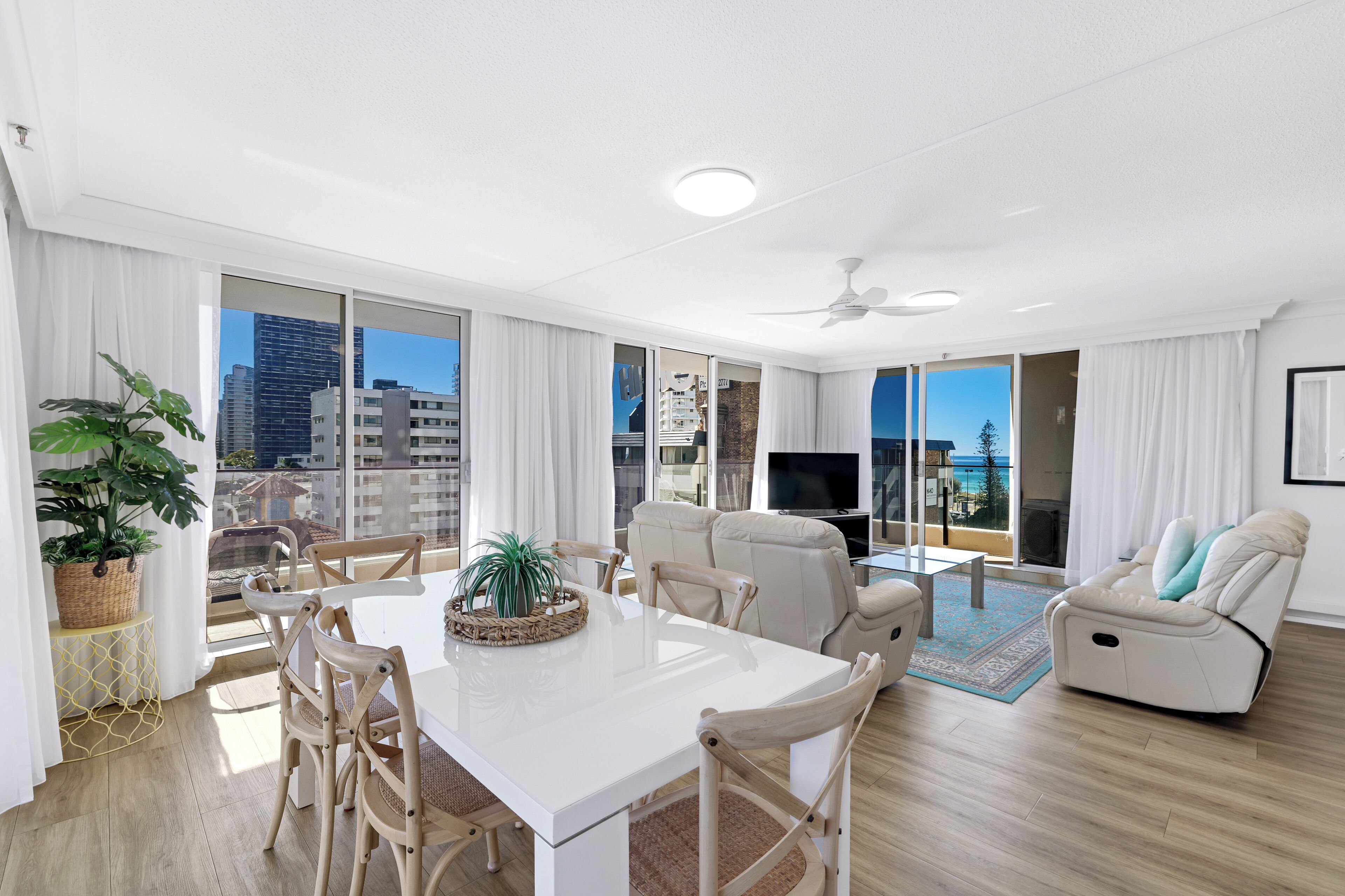 Un salon moderne avec un coin repas, de grandes fenêtres et une vue sur la ville.