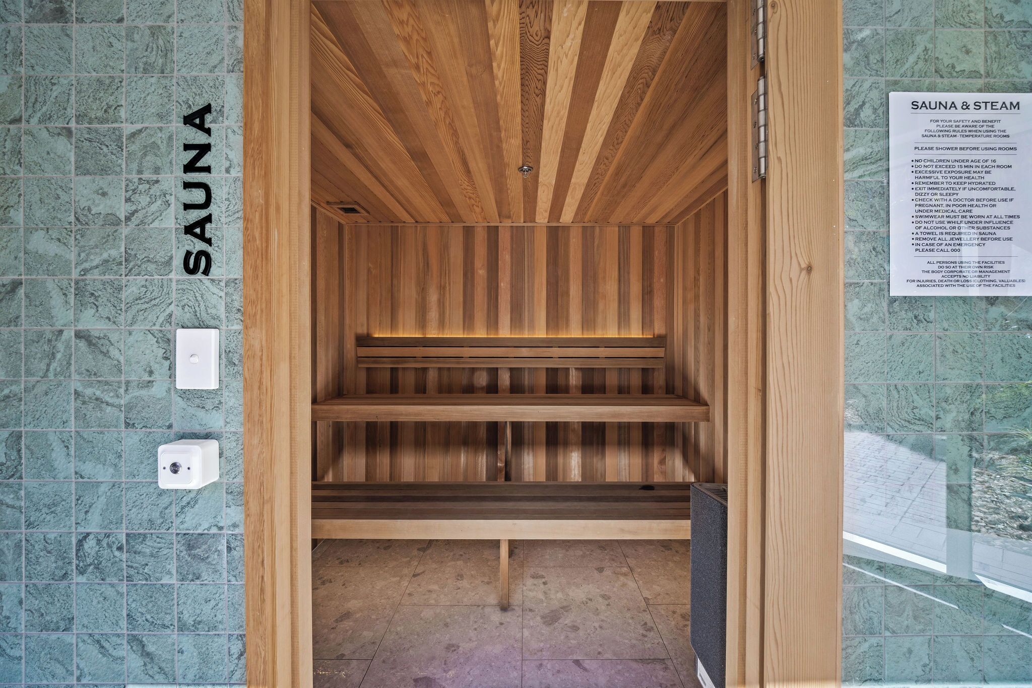 Een sauna met houten banken en een betegelde muur.