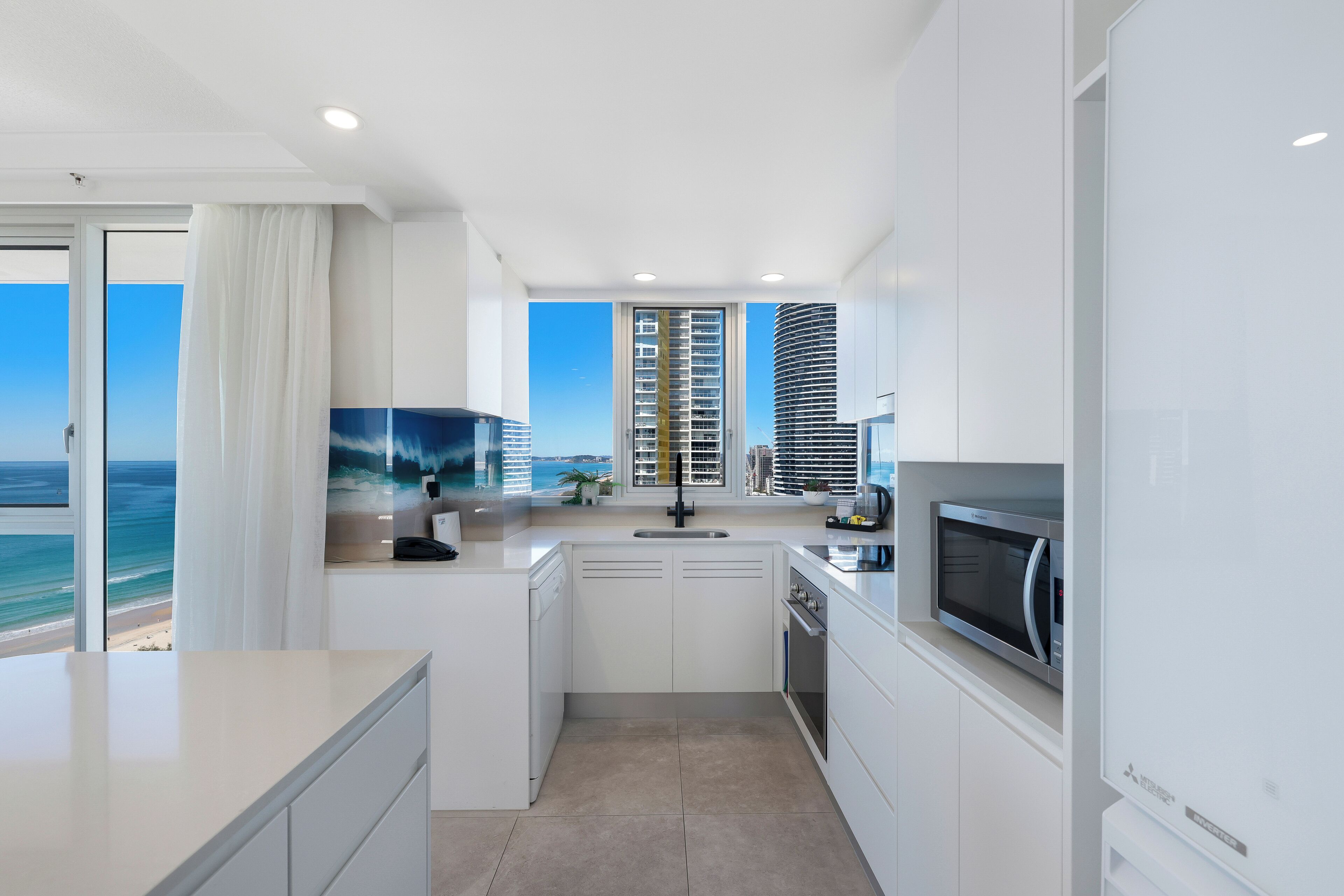 A modern kitchen with white cabinetry, a microwave, and a sink.